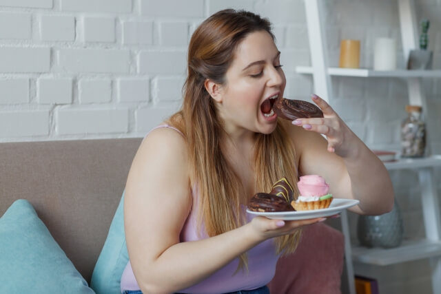甘いものが大好きでケーキを大量に食べている太った女性